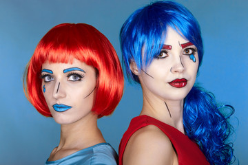 Obraz premium Portrait of young women in comic pop art make-up style. Females in red and blue wigs on blue background