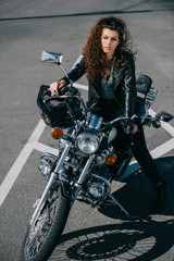 Fototapeta na wymiar attractive curly girl sitting on classical motorbike with helmet on parking