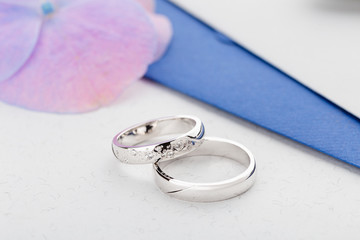 Two silver wedding rings with diamonds on gray background