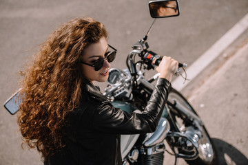 Obraz na płótnie Canvas beautiful girl sitting on classical motorbike on parking