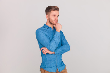 pensive casual man in blue denim shirt looks to side