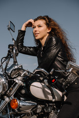 Fototapeta na wymiar attractive female biker sitting on vintage classical motorbike
