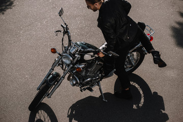 young biker sitting on vintage classical motorcycle on road