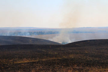 Burnt out smoking steppe after disastrous fire