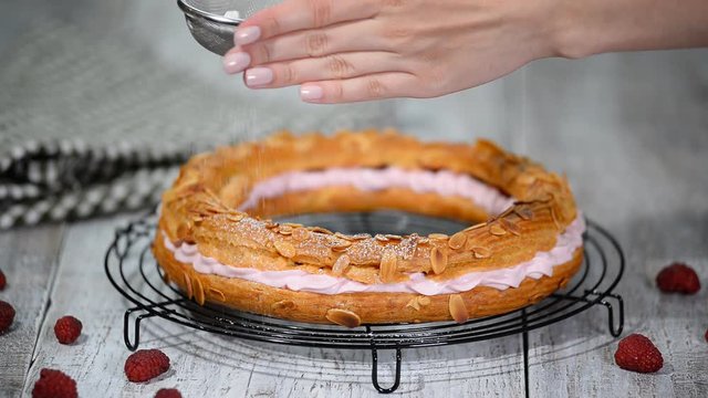 Sifting powdered sugar over a paris brest.