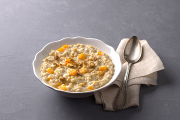 Pumpkin oatmeal with honey and nuts on a gray background. healthy delicious homemade breakfast