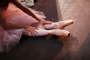 Ballerina in pointe shoes, sitting on the floor behind the scenes in the intermission of the ballet