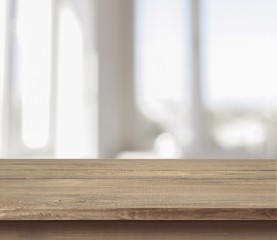 Brown desk in a white empty room lit by the sun