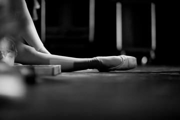 Ballerina in pointe shoes, sitting on the floor behind the scenes in the intermission of the ballet