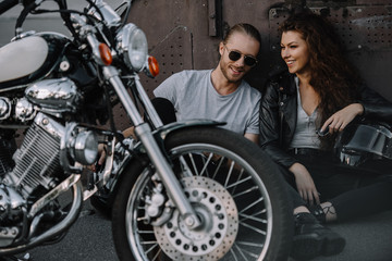 Naklejka na ściany i meble couple of bikers sitting on asphalt with chopper motorcycle