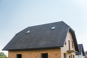 Natural brown roof tiles on a building against blue sky.