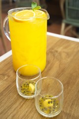 big glass jar with orange and passion fruit juice on a wooden background, space for text. colorful drinks. Natural fruit ingredients for drinks
