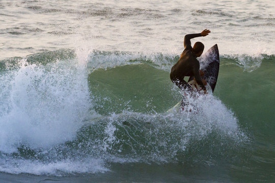 SURFISTA EN EL MAR SURFEANDO AL ATARDECER
