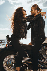 Fototapeta na wymiar couple of bikers in black leather jackets hugging on chopper motorcycle