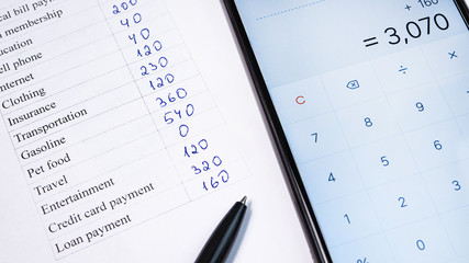 Home budget planning sheet with pen and smart phone calculator