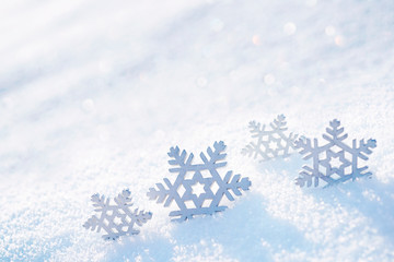 Light soft Christmas background. Decorative snowflakes close-up macro in snow on nature in rays of sunlight, copy space.