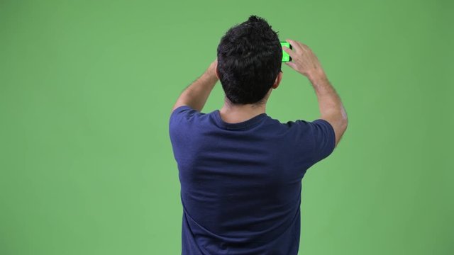Rear view of Hispanic man photographing with phone