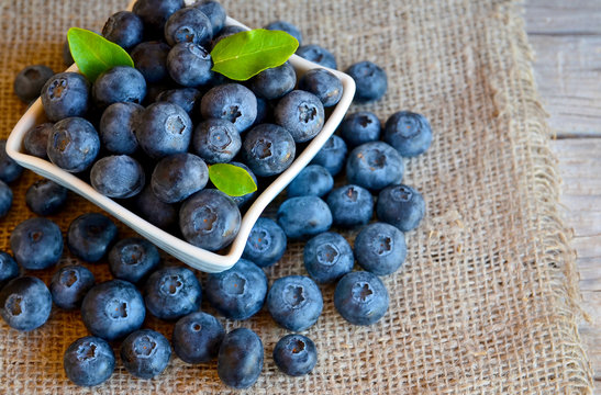 Freshly picked blueberries in a bowl on a burlap cloth background.Fresh organic blueberry.
Bilberries.Healthy eating,vegan diet or raw food concept.Selective focus.