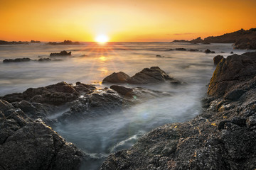 Fototapeta na wymiar Romantic sunset over rocky coast and soft silky water