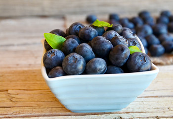Freshly picked blueberries in a bowl on old wooden background.Fresh organic blueberry.
Bilberries.Selective focus.