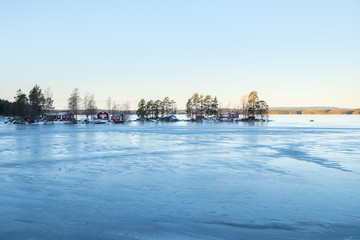 Fototapeta na wymiar Winter landscape with red wooden house on a lake in Sweden.