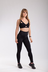Sport woman in sport style clothes. Attractive and sportive woman in black leggings and black top. Isolated on white background