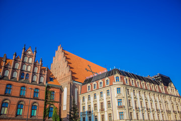 old city street view concept of red roofs of medieval catholic cathedral church buildings facade on empty blue sky background 