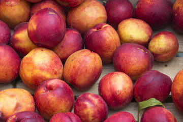 ripe peaches in a box at a farmers market with local produce