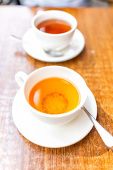 Closeup of two white cups on plates of green or oolong tea in breakfast brunch outdoor cafe restaurant outside wooden table with orange colorful vibrant saturated color