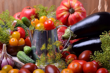 Cherry tomatoes in a metallic jug surrounded by different vegetables