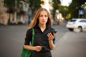 young woman with credit card and smartphone in hand on the background of old city street