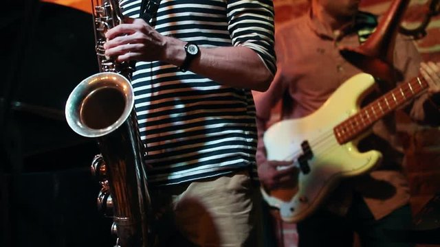 Saxophonist and guitarist masterly play at a performance in a jazz bar