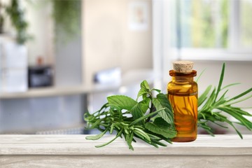 Oil bottle and green herbs on blue background