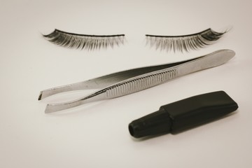 False eyelash, tweezer, glue tube, isolated on white background. Items for women's beauty. 
