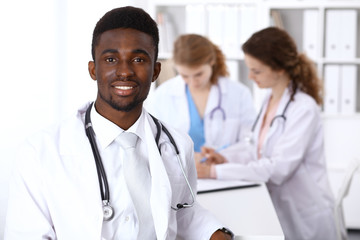 Fototapeta premium Happy african american male doctor with medical staff at the hospital. Medicine concept