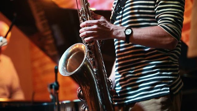 Musician-saxophonist playing an instrument at a party in a jazz bar in the frame only his hands
