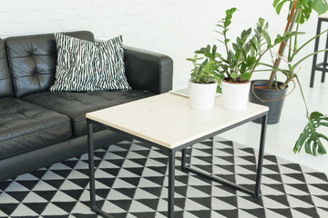 Interior, furniture concept - a white table is standing in a room near the black leather sofa