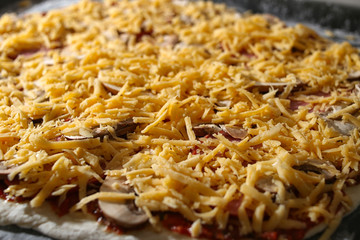 Stages of cooking pizza. Sauce, mushrooms, cheese and sausage rolled up dough.