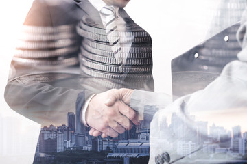 The double exposure image of the businessman handshaking with another one during sunrise overlay with cityscape and coin stack image. The concept of modern life, business, city life and partnership.