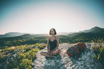 Girl is sitting on the top of the mountain.