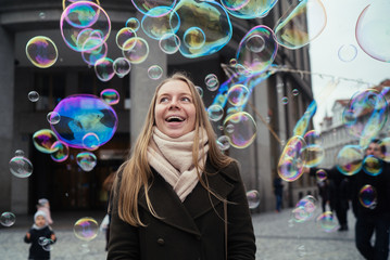 happy girl in a coat on the street in the city and soap bubbles