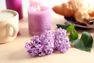 Beautiful blossoming lilac with burning candle on table