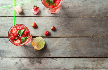 Fototapeta na wymiar Glasses with strawberry mojito on wooden table