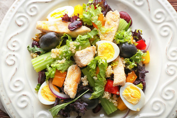Tasty chicken salad with vegetables and quail eggs on plate, closeup