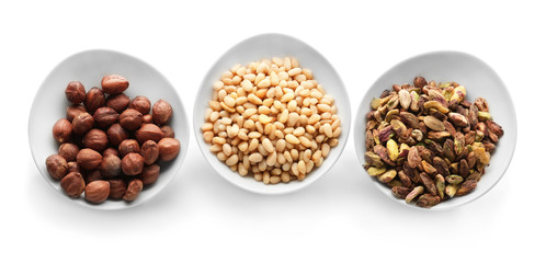 Bowls with tasty nuts on white background