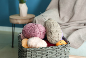 Fototapeta na wymiar Wicker basket with knitting yarn and needles in room