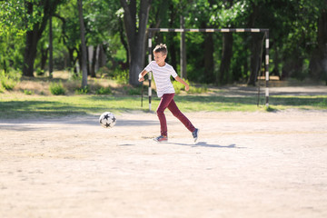 Little boy playing football on soccer pitch