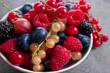 Bowl with different ripe berries on table, closeup