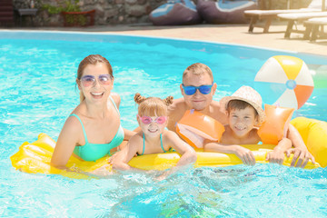 Happy family with inflatable mattress in swimming pool