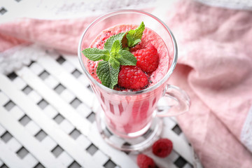 Glass with tasty raspberry smoothie on table